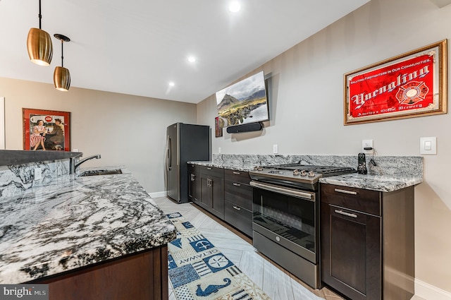 kitchen with dark brown cabinetry, pendant lighting, light stone counters, appliances with stainless steel finishes, and a sink