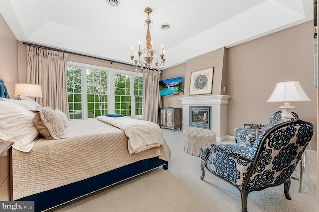 carpeted bedroom with an inviting chandelier, visible vents, and a tray ceiling