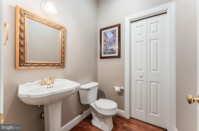 half bathroom featuring baseboards, toilet, and wood finished floors