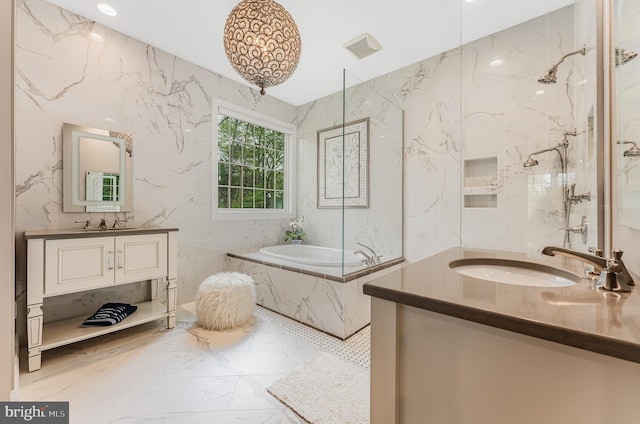 full bath with marble finish floor, two vanities, a sink, stone wall, and a bath