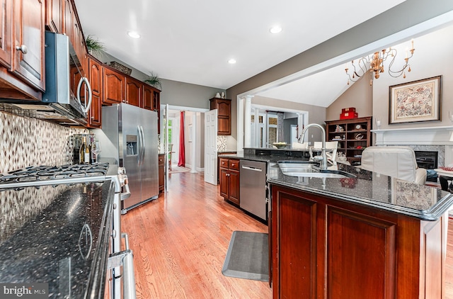 kitchen with light wood-type flooring, a sink, decorative backsplash, appliances with stainless steel finishes, and open floor plan