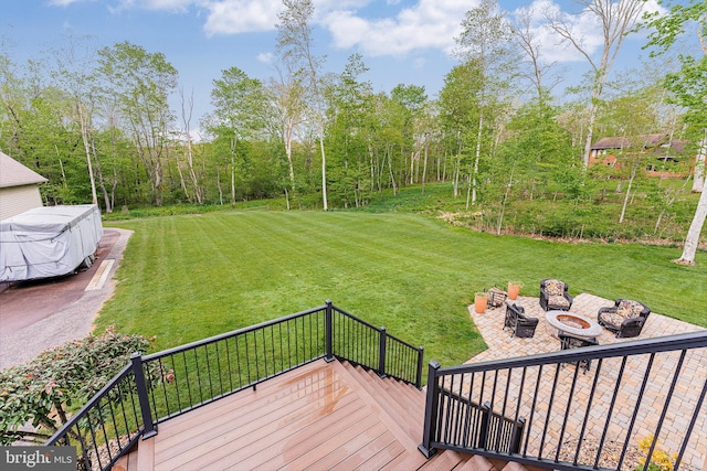 wooden terrace with a fire pit and a lawn