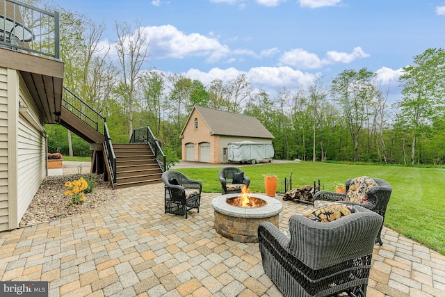 view of patio with stairs, an outbuilding, a fire pit, and a garage