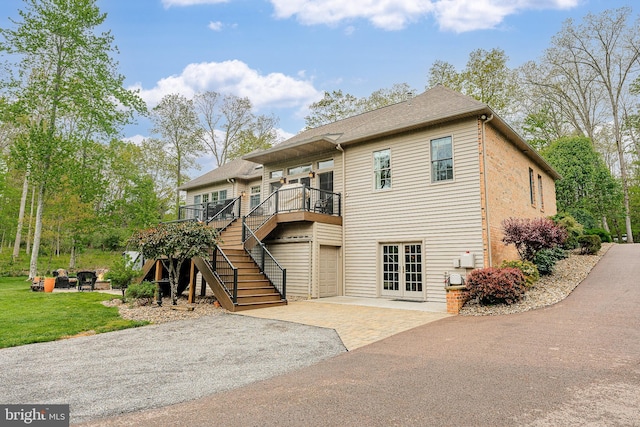 view of front of property with stairs, french doors, a deck, a garage, and driveway