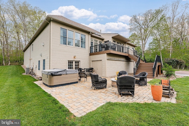 rear view of property featuring stairway, a patio area, a lawn, and a hot tub