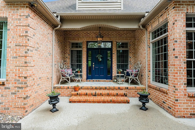 property entrance featuring brick siding and a porch