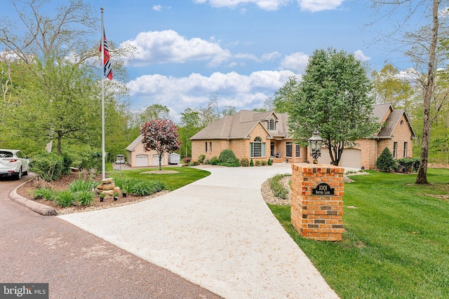 view of front of property featuring brick siding, curved driveway, and a front yard