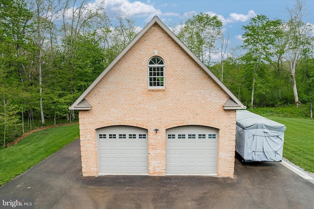 view of home's exterior with brick siding, aphalt driveway, and a yard