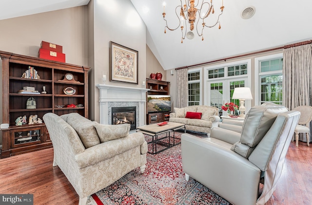 living room with a notable chandelier, wood finished floors, visible vents, and a premium fireplace