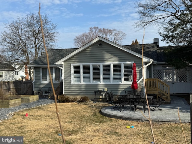 back of house with a yard, a shingled roof, fence, and a patio