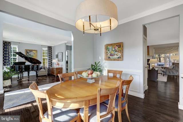 dining space with ornamental molding, a wainscoted wall, an inviting chandelier, and wood finished floors