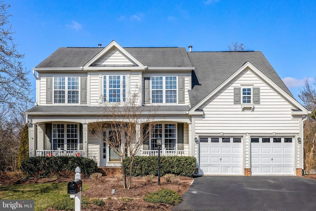 traditional-style home with a porch, an attached garage, and aphalt driveway