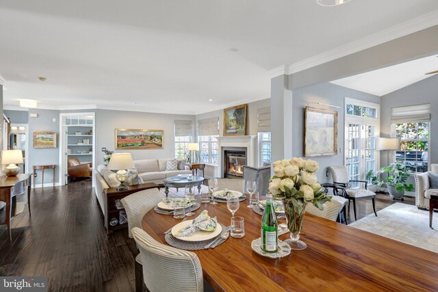 dining room with a healthy amount of sunlight, ornamental molding, wood finished floors, and a glass covered fireplace