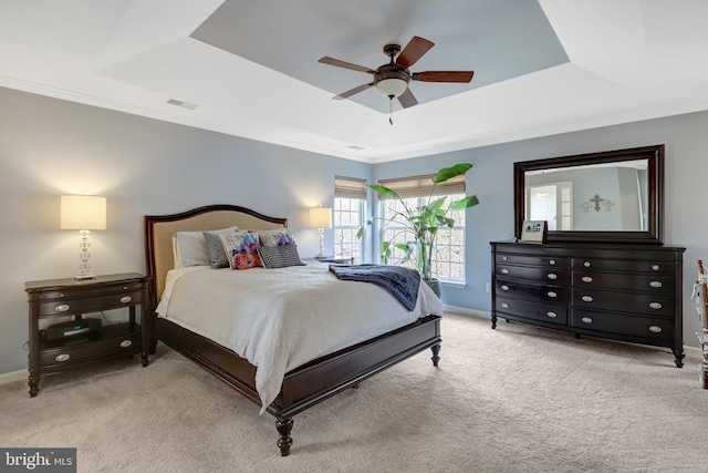 carpeted bedroom featuring ornamental molding, a tray ceiling, visible vents, and baseboards