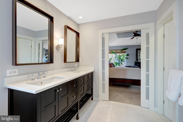 bathroom with connected bathroom, double vanity, a sink, and a ceiling fan