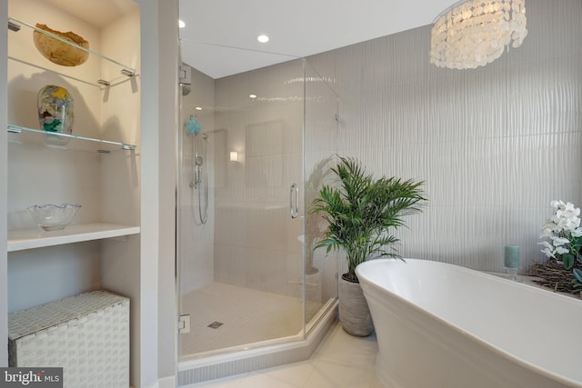 bathroom with tile walls, a freestanding tub, a shower stall, and tile patterned floors