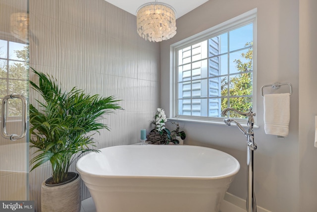 bathroom featuring a freestanding tub and an inviting chandelier