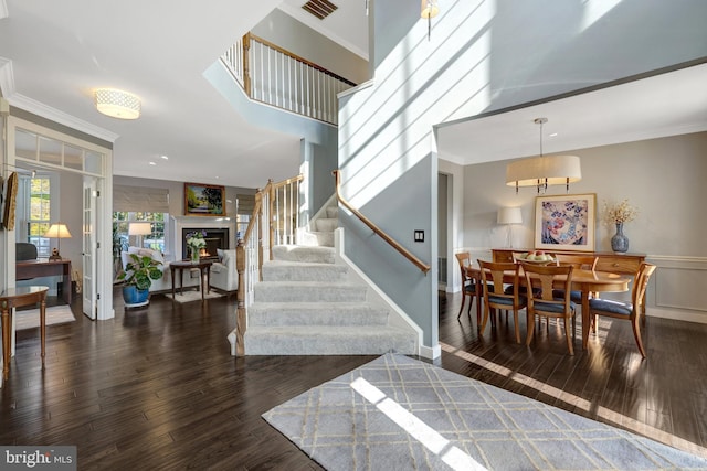 foyer entrance with ornamental molding, wood finished floors, wainscoting, and stairs