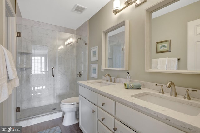 full bathroom featuring a stall shower, visible vents, a sink, and toilet