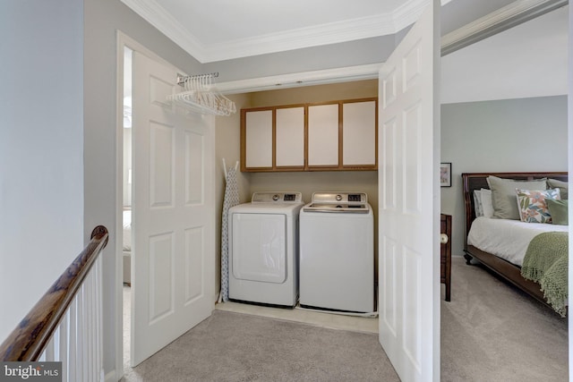 washroom featuring light colored carpet, washing machine and dryer, cabinet space, and crown molding