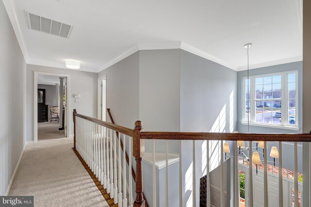 corridor featuring carpet floors, visible vents, ornamental molding, an upstairs landing, and baseboards