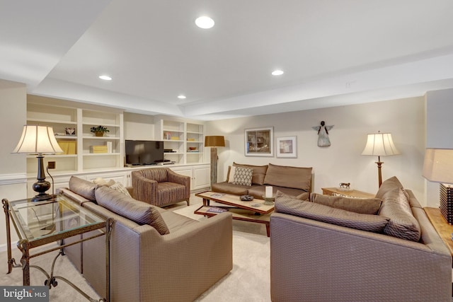 living area featuring a raised ceiling and recessed lighting