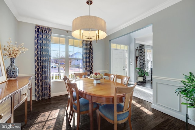 dining area featuring dark wood-type flooring, wainscoting, a wealth of natural light, and crown molding