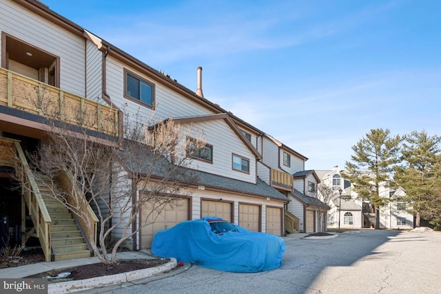 view of front of property featuring stairs, an attached garage, and a residential view