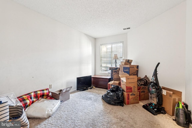 interior space featuring carpet flooring, visible vents, and a textured ceiling