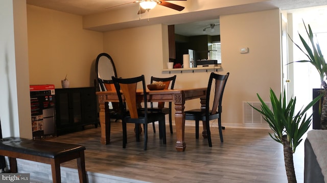 dining room featuring baseboards, ceiling fan, visible vents, and wood finished floors