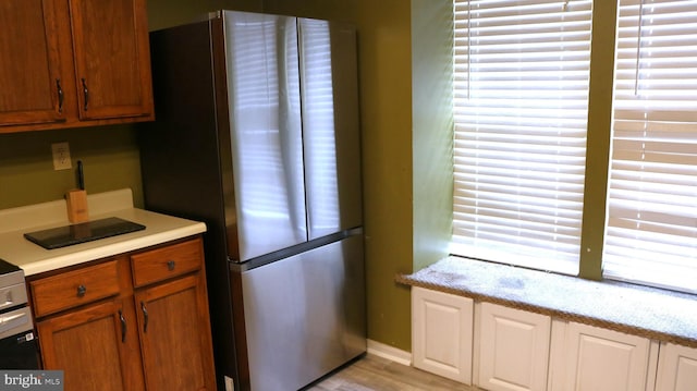 kitchen with brown cabinets, light wood finished floors, light countertops, and freestanding refrigerator