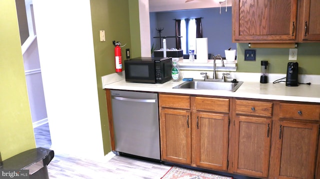 kitchen with black microwave, light countertops, stainless steel dishwasher, and a sink