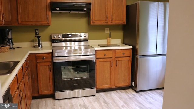 kitchen with appliances with stainless steel finishes, brown cabinetry, light countertops, and exhaust hood