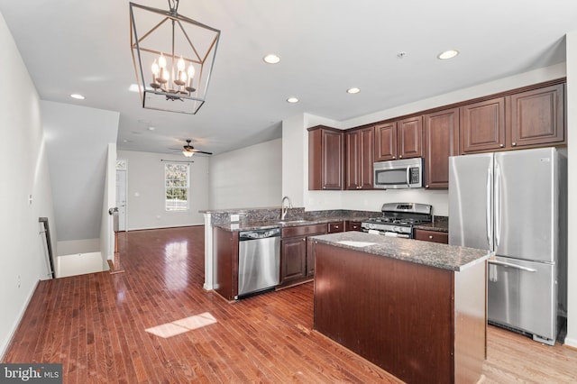 kitchen with recessed lighting, stainless steel appliances, a kitchen island, a sink, and light wood-style floors