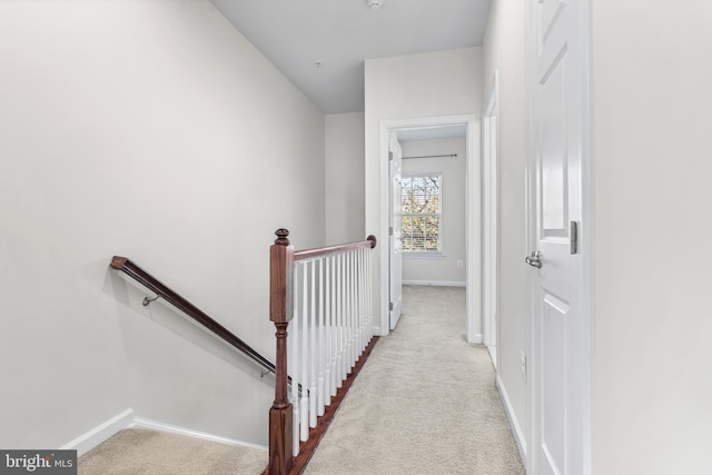 hallway with baseboards, carpet flooring, and an upstairs landing