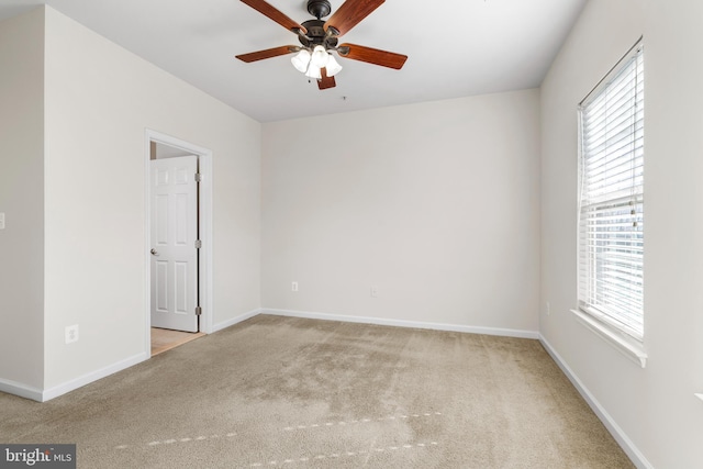 carpeted empty room with ceiling fan, a wealth of natural light, and baseboards