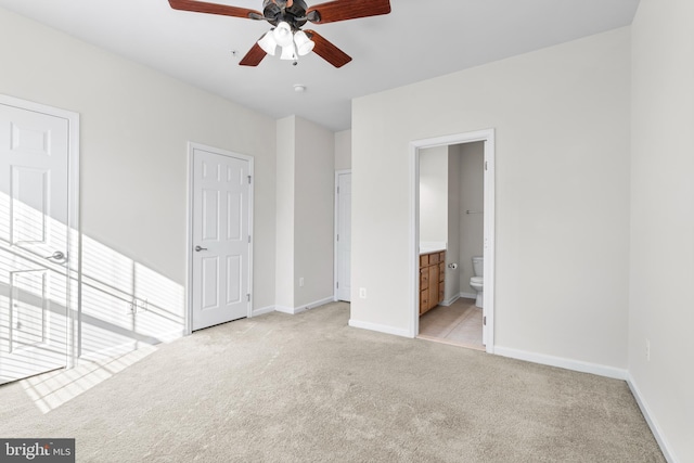 unfurnished bedroom with light carpet, ensuite bathroom, and baseboards