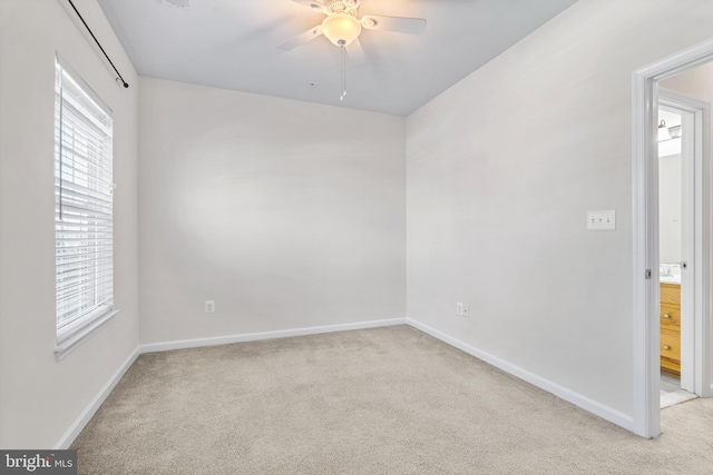 unfurnished room with baseboards, a ceiling fan, and light colored carpet