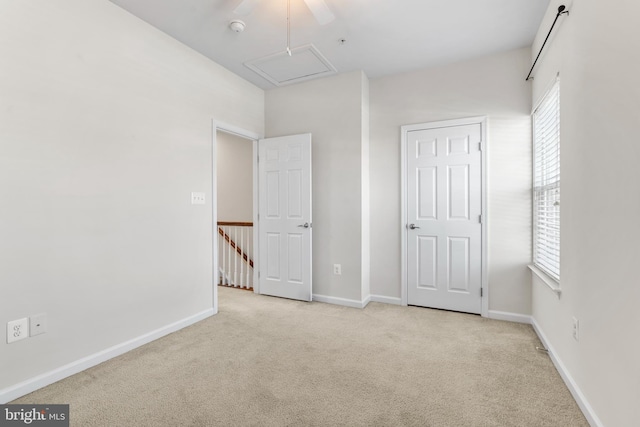 unfurnished bedroom with carpet floors, attic access, a ceiling fan, and baseboards