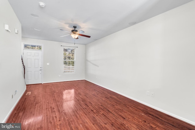 empty room featuring ceiling fan, baseboards, and wood finished floors