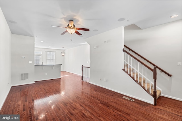 unfurnished living room featuring stairway, hardwood / wood-style flooring, visible vents, and baseboards