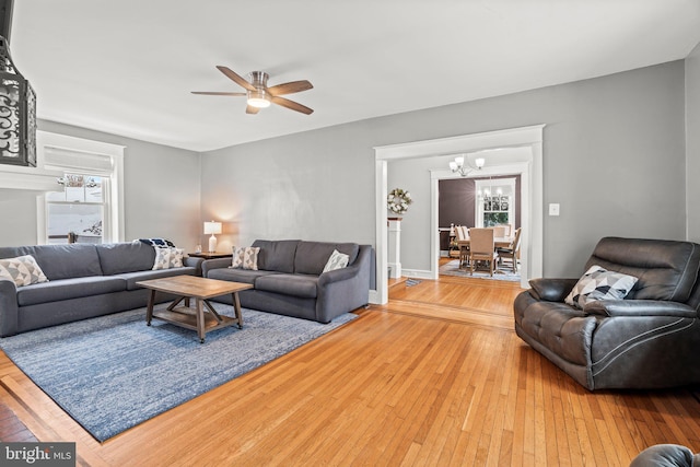 living room with light wood finished floors and ceiling fan with notable chandelier