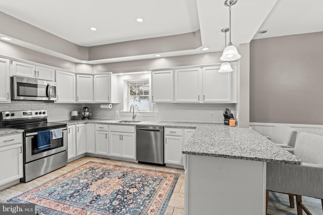 kitchen with stainless steel appliances, a breakfast bar, a peninsula, a sink, and backsplash