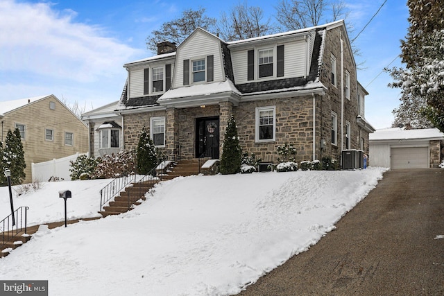 dutch colonial featuring an outbuilding, a garage, central AC, a gambrel roof, and a chimney