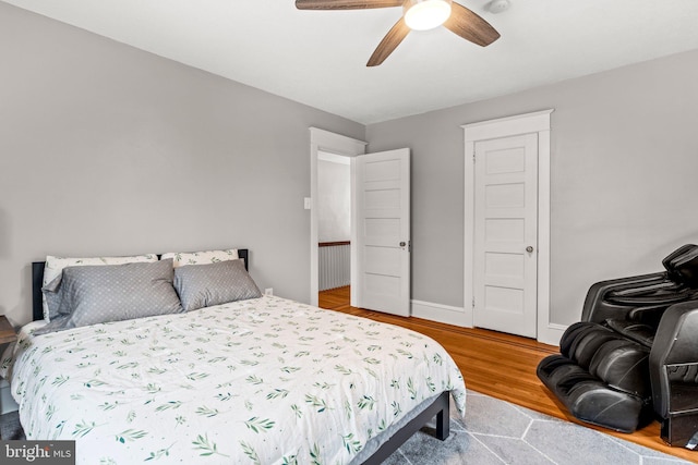 bedroom featuring wood finished floors, a ceiling fan, and baseboards