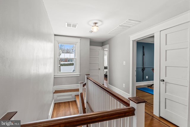 staircase with baseboards, visible vents, and wood finished floors