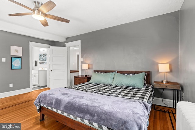 bedroom featuring ensuite bath, radiator heating unit, baseboards, and wood finished floors