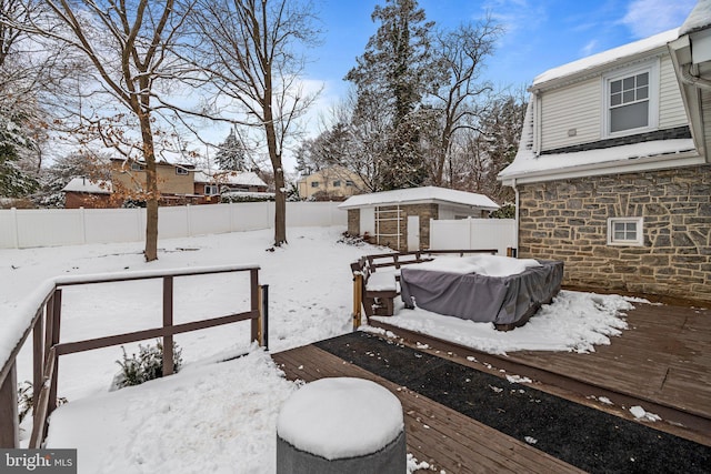 yard covered in snow with an outbuilding, a fenced backyard, and a wooden deck