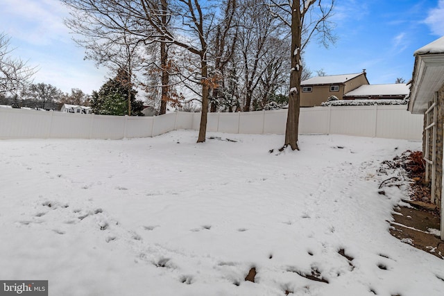 yard layered in snow with a fenced backyard