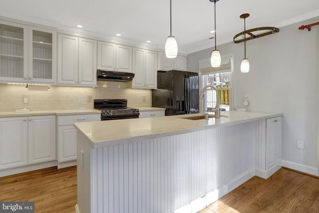 kitchen featuring light wood-type flooring, black appliances, under cabinet range hood, white cabinetry, and a peninsula